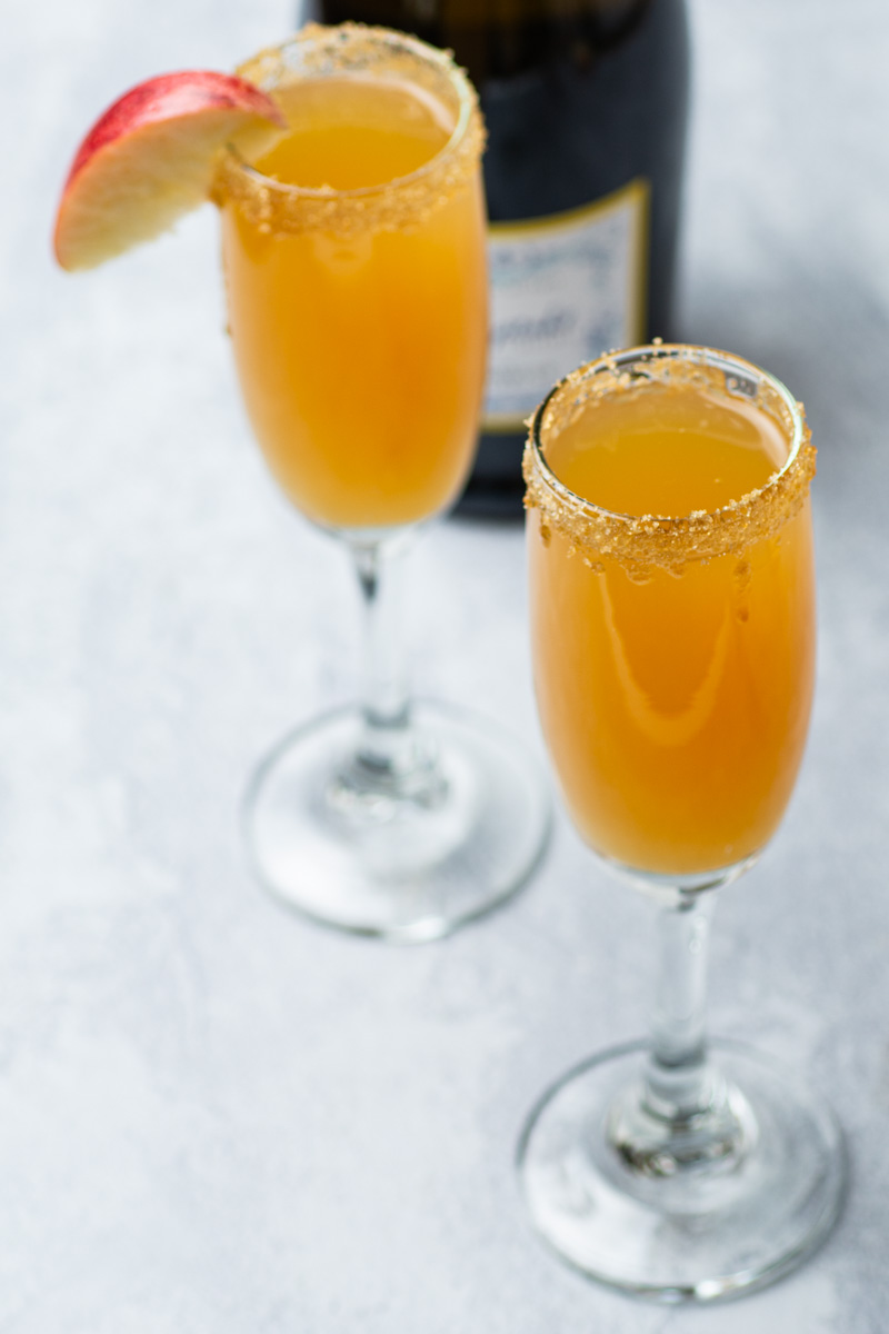 Apple cider mimosas in flute glasses with brown sugar lined rim.