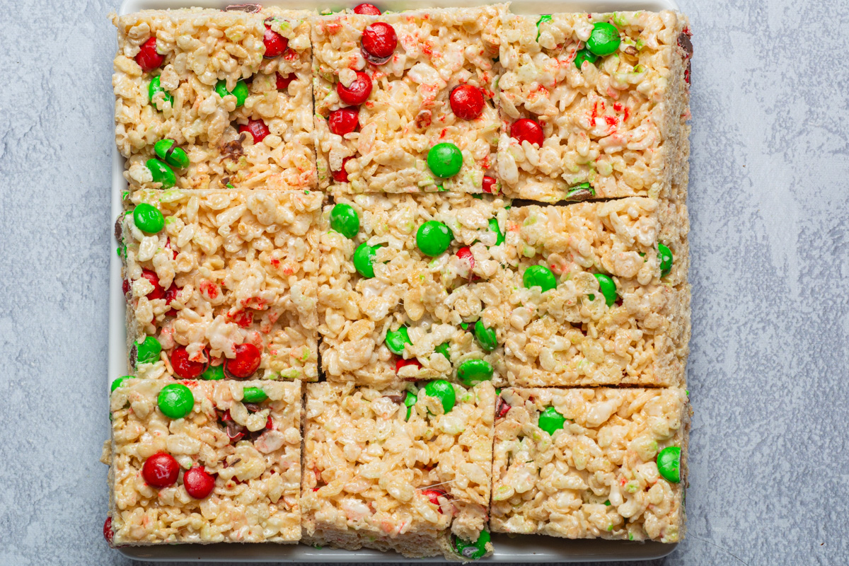 A plate full of nine square rice krispie treats with festive M&M's.