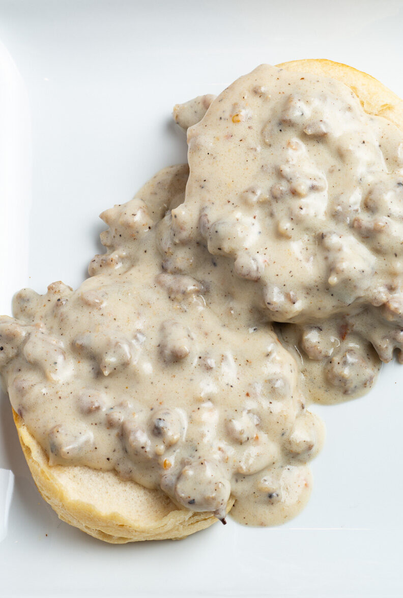Biscuits and old fashioned sausage gravy on a white plate.